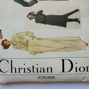 May include: Vintage Vogue Paris Original sewing pattern featuring Christian Dior designs. The pattern cover displays illustrations of three different outfits: a long coat, a dress, and a skirt and top combination. The cover is off-white with the Vogue and Christian Dior logos.