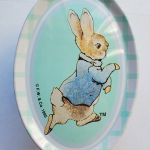 May include: Oval metal tray featuring a cartoon rabbit in a blue jacket, set against a light blue background. The tray has a checkered border in white and light green. The text "© F.W. & Co. 1995 TM" is printed on the tray.