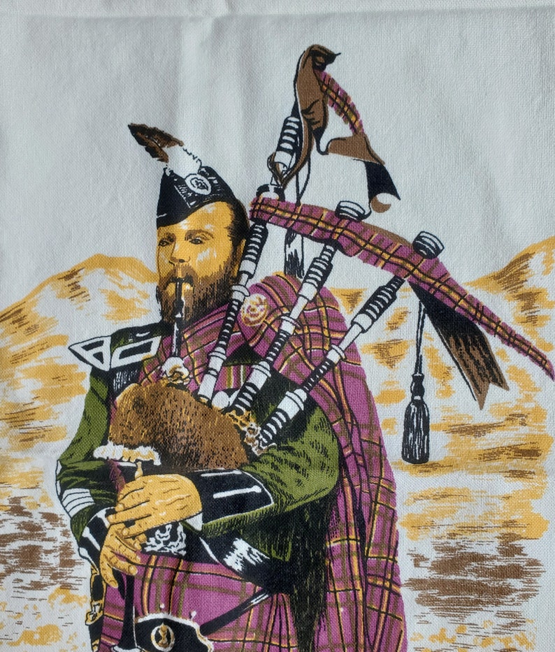 May include: A printed image of a Scottish bagpiper in traditional attire. The bagpiper is wearing a plaid kilt and cape in shades of purple, green, and yellow. The background features a landscape with yellow and brown tones.