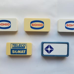 May include: Five rectangular erasers arranged in two rows. Three white and cream erasers feature the blue and orange SOHIO logo. One cream eraser displays the blue TELECO SONAT logo. One white eraser with a blue border features a blue four-pointed star.