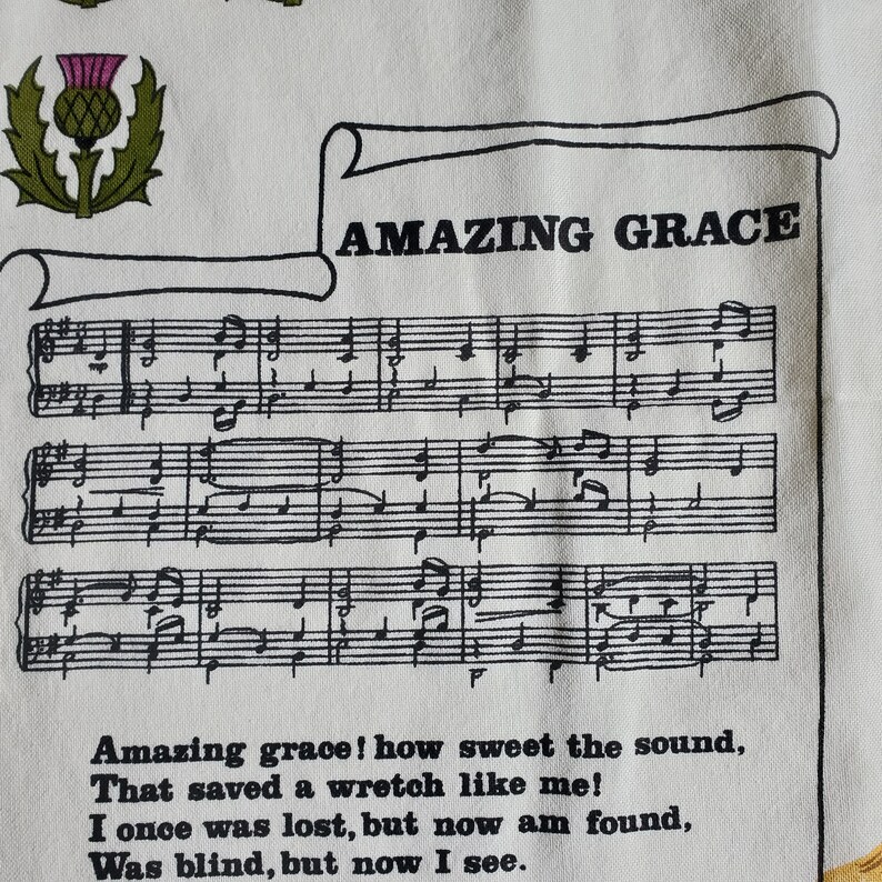 May include: White fabric featuring the text "AMAZING GRACE" above musical notation. The lyrics "Amazing grace! how sweet the sound, That saved a wretch like me!" are printed below the musical score. A thistle emblem is in the upper left corner.