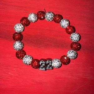 May include: Red and white beaded bracelet with silver-toned '22' charm.