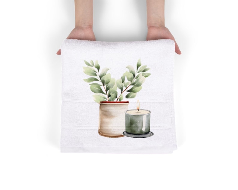 May include: White hand towel with a watercolor design of a potted plant and a lit candle. The plant has green leaves and is in a beige pot. The candle is in a clear glass holder with a gray base.