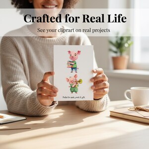 Peut inclure: Une personne tient une carte avec deux illustrations de cochons de dessin anim&eacute;. L'un porte des livres, l'autre joue de la trompette. La carte affiche le texte "Crafted for Real Life" et "See your clipart on real projects". Le bas indique "Perfect for cards, prints & gifts."
