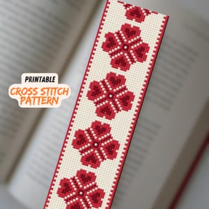 May include: Printable cross stitch pattern for a bookmark featuring a repeating design of red flowers on a white background. The text "Printable Cross Stitch Pattern" is visible in the image.