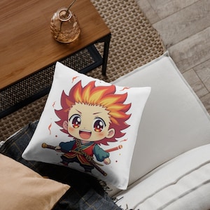 K&ouml;nnte beinhalten: Quadratisches wei&szlig;es Kissen mit einer Anime-Cartoon-Figur mit roten und gelben Haaren, die ein Schwert h&auml;lt. Die Figur tr&auml;gt ein rot-gr&uuml;nes Outfit. Das Kissen liegt auf einem wei&szlig;en Sofa, im Hintergrund ein Holztisch.