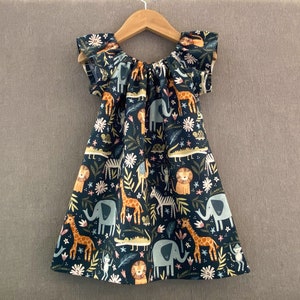 May include: A dark blue dress with a ruffle neckline and short sleeves. The dress features a whimsical print of animals, including elephants, giraffes, lions, and monkeys, in a jungle setting.