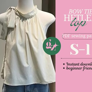 Può includere: Un top color crema con dettaglio a fiocco, esposto su un manichino. Il top ha un collo alto e una silhouette fluida. Il testo a destra recita "BOW TIE HETLER top" e "S-1". Lo sfondo è rosa.