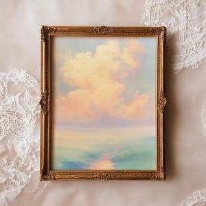 Puede incluir: Pintura de paisaje enmarcada con un marco dorado ornamentado. La obra de arte representa un cielo pastel con nubes esponjosas en tonos melocotón y amarillo, reflejándose en una masa de agua con tonos azules y verdes.