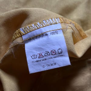 May include: A white tag with black text and symbols. The tag says "Polyester 100%" and includes washing instructions. The tag also has the code "C-TK3639".