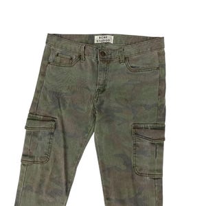 Puede incluir: Pantalones cargo de camuflaje verde con la etiqueta "ACNE STUDIOS". Los pantalones tienen dos bolsillos cargo en las piernas y bolsillos delanteros y traseros est&aacute;ndar. Los pantalones est&aacute;n hechos de una tela duradera.