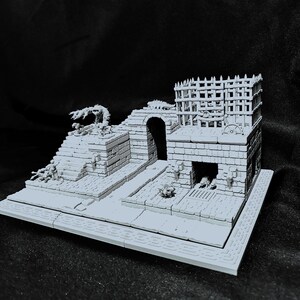 Puede incluir: Una maqueta gris de una fortaleza con un dise&ntilde;o de varios niveles. El modelo presenta un arco central, una torre con una parte superior enrejada y un trabajo de ladrillo detallado. Peque&ntilde;os elementos decorativos y una base con un borde estampado completan la escena.