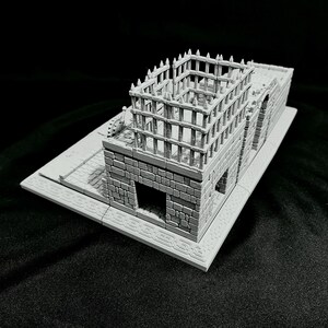 Puede incluir: Modelo en miniatura gris de un edificio con textura de piedra. La estructura presenta una base rectangular, una fachada detallada con puertas arqueadas y una estructura en forma de jaula en el tejado. Modelo para juegos de mesa o exhibici&oacute;n.