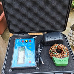 May include: A black hard-shell carrying case with foam lining containing a blue FG-200 DDS function generator, a black power adapter with a cord, and a circular coil component with copper wiring and a green base labeled Tanso.ph.