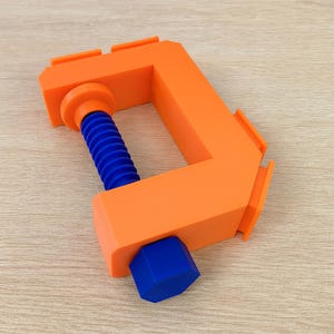 May include: An orange C-clamp with a blue threaded rod and a blue hexagonal nut. The clamp is made of plastic and is designed to hold objects together. The clamp is a useful tool for woodworking, construction, and other DIY projects.