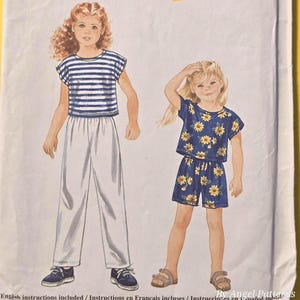 May include: A vintage sewing pattern titled "It's SO EASY it's Simplicity ...for Kids." The pattern features illustrations of two children's outfits: a striped top with white pants and a floral print top and shorts. The pattern size is A 2,3,4,5,6,6X.