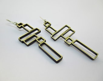 May include: A pair of gold-toned geometric earrings with a modern design. The earrings are made of multiple interconnected rectangular shapes.