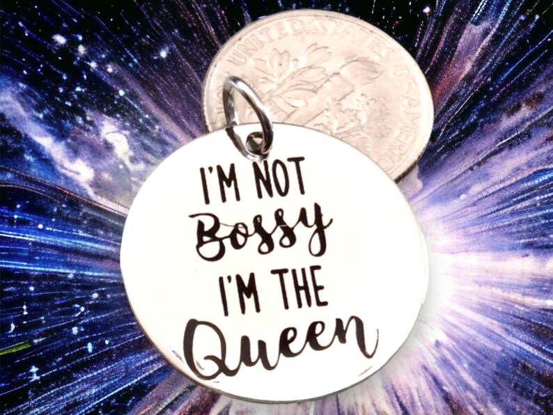 May include: A silver charm with the text "I'm not bossy I'm the Queen" in black lettering.