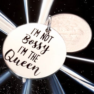 May include: Silver charm with the text "I'm not bossy I'm the Queen" in black lettering.
