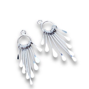 May include: A pair of silver earrings with a circle design and multiple dangling teardrop shapes.