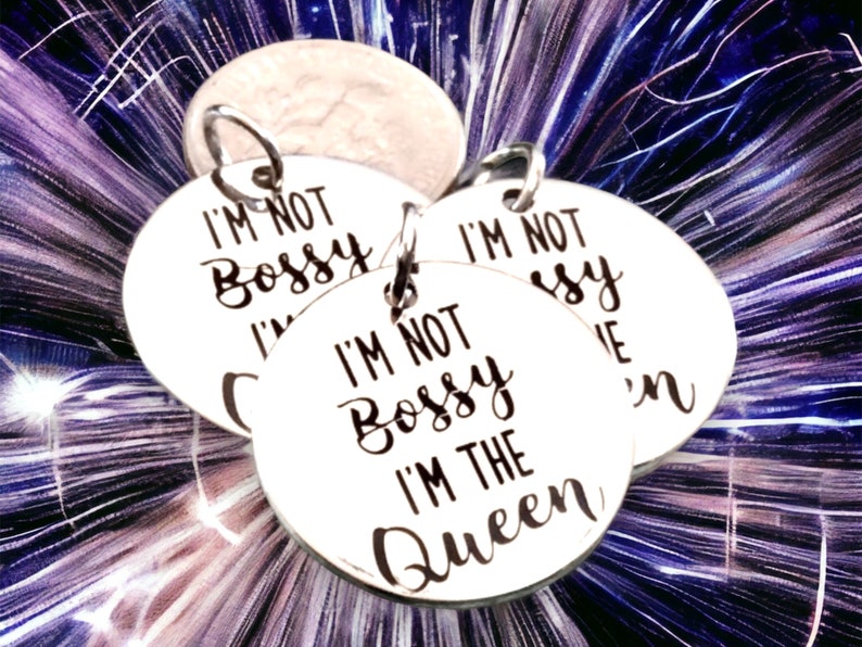 May include: Three silver round charms with the text "I'm not bossy I'm the queen" on them.