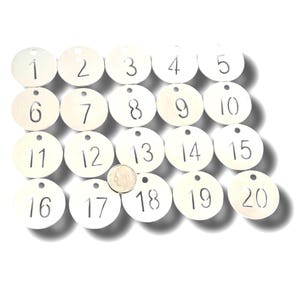 May include: Twenty white, circular tags with numbers 1 through 20 printed in black. Each tag has a small hole at the top. A dime is placed near the center of the tags for size comparison.