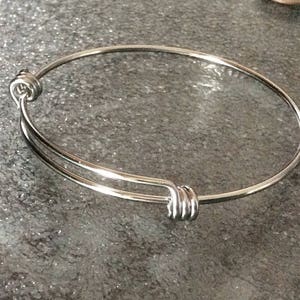 May include: A silver expandable bangle bracelet with a simple design.