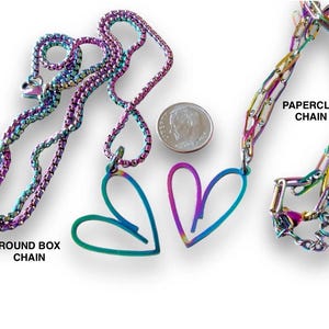 May include: Two iridescent necklaces with heart pendants. One necklace has a round box chain and the other has a paperclip chain. The text "ROUND BOX CHAIN" and "PAPERCLIP CHAIN" is below each necklace.