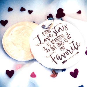 May include: A white wooden round ornament with a brown inscription that reads "Every love story is beautiful but ours is my favorite". The ornament is surrounded by small hearts of various colors.