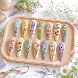May include: A wooden tray displays 12 embroidered hair clips, each with a unique floral design. The clips showcase various flowers such as lavender, daisies, and sunflowers, in pastel shades. A pair of gold scissors and a spool of thread are in the foreground.