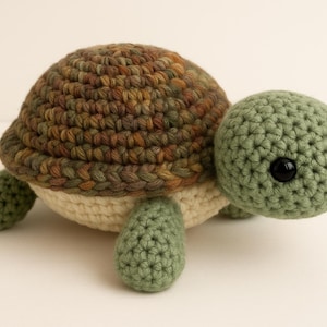 Puede incluir: Una tortuga de ganchillo hecha a mano. El caparazón es de hilo marrón y verde, la cabeza y las patas son verdes y la parte inferior es crema. La tortuga tiene ojos negros. Hecho a mano.