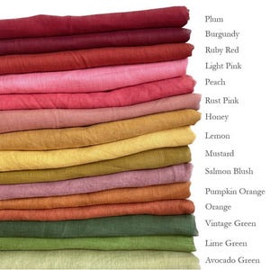 May include: A stack of 15 fabric swatches in various shades of red, pink, orange, yellow, green, and brown. The swatches are labelled with the colour names: Plum, Burgundy, Ruby Red, Light Pink, Peach, Rust Pink, Honey, Lemon, Mustard, Salmon Blush, Pumpkin Orange, Orange, Vintage Green, Lime Green, and Avocado Green.