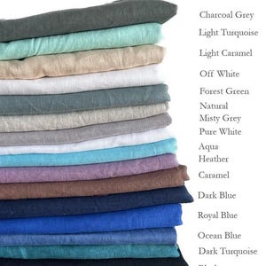 May include: A stack of folded linen fabric in various colors, including charcoal grey, light turquoise, and dark blue. The image also displays the names of the colors: Charcoal Grey, Light Turquoise, Light Caramel, Off White, Forest Green, Natural, Misty Grey, Pure White, Aqua, Heather, Caramel, Dark Blue, Royal Blue, Ocean Blue, Dark Turquoise, and Black.