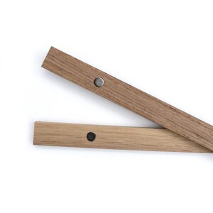 May include: Two wooden picture frame rails with metal magnetic closures. The rails are light brown and the magnets are silver.