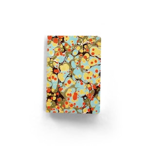May include: A small notebook with a marbled cover. The cover features a pattern of blue, yellow, orange, and brown organic shapes. The notebook is rectangular and appears to be closed.