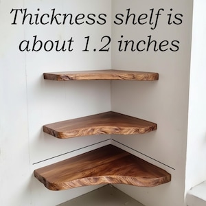 Op de afbeelding: Drie houten hoekplanken met een natuurlijke rand zijn aan een witte muur bevestigd. De planken zijn driehoekig en hebben een rijke bruine kleur. De tekst "Thickness shelf is about 3 cm" is zichtbaar.