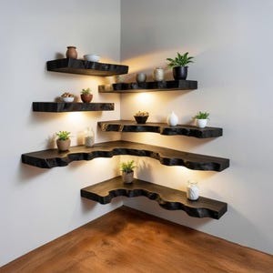 May include: A set of dark wood floating shelves installed in a corner, with a live edge design. The shelves are illuminated from below and display small potted plants and decorative items. The shelves are a dark brown color.