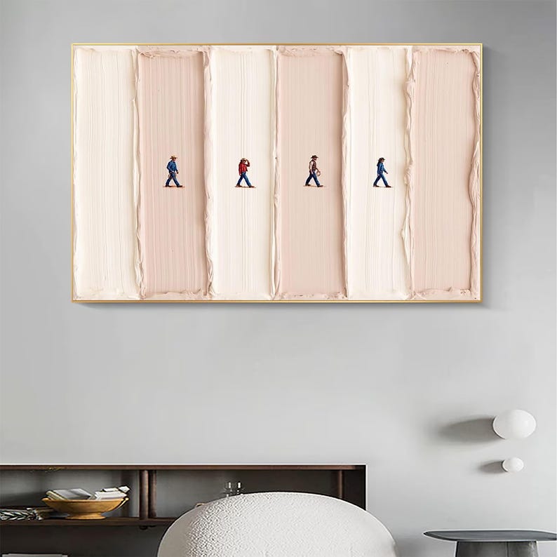 May include: Abstract art piece featuring four tiny figures walking across vertical bands of textured, light pink and white paint. The artwork is framed in a gold-colored border, creating a modern and minimalist aesthetic. The figures are wearing different colored outfits.