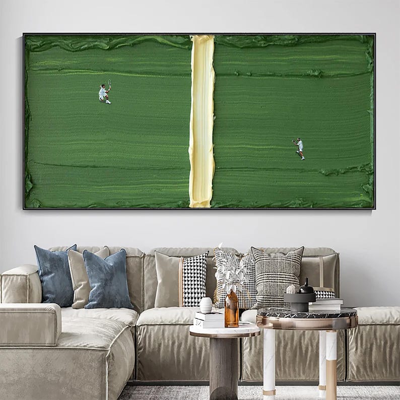 Puede incluir: Pintura abstracta enmarcada que representa una cancha de tenis con dos jugadores. La cancha es verde texturizado con una l&iacute;nea central amarilla. Los jugadores son peque&ntilde;as figuras en blanco. La pintura est&aacute; sobre un sof&aacute; con cojines.