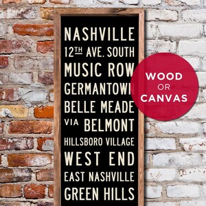 May include: Black sign with white text listing Nashville neighborhoods, including Music Row, Germantown, Belle Meade, and West End. The sign is framed in wood and has a red circle with the text "WOOD OR CANVAS" in white.