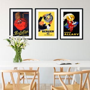 Puede incluir: Tres carteles vintage enmarcados con ilustraciones y texto coloridos. El cartel de la izquierda presenta a un hombre con barba roja que lleva un sombrero y el texto "Vodka Relshup f KUMEL". El cartel del medio presenta a un hombre con esmoquin que sostiene una bandeja con una botella y el texto "Berger 45 Type Marseillais". El cartel de la derecha presenta a un hombre con un traje rojo que sostiene una gran copa de cerveza y el texto "Biere Allary".