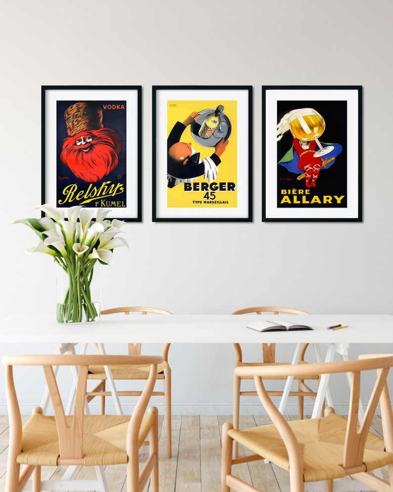 Puede incluir: Tres carteles vintage enmarcados con ilustraciones y texto coloridos. El cartel de la izquierda presenta a un hombre con barba roja que lleva un sombrero y el texto "Vodka Relshup f KUMEL". El cartel del medio presenta a un hombre con esmoquin que sostiene una bandeja con una botella y el texto "Berger 45 Type Marseillais". El cartel de la derecha presenta a un hombre con un traje rojo que sostiene una gran copa de cerveza y el texto "Biere Allary".