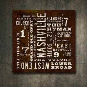 A brown and white typography poster by Transit Design with the word 'Nashville' in large white letters. The poster also includes other words related to Nashville, such as 'Music Row', 'The Ryman', '12th South', 'The Gulch', and 'West End'. The poster has a distressed, vintage look.