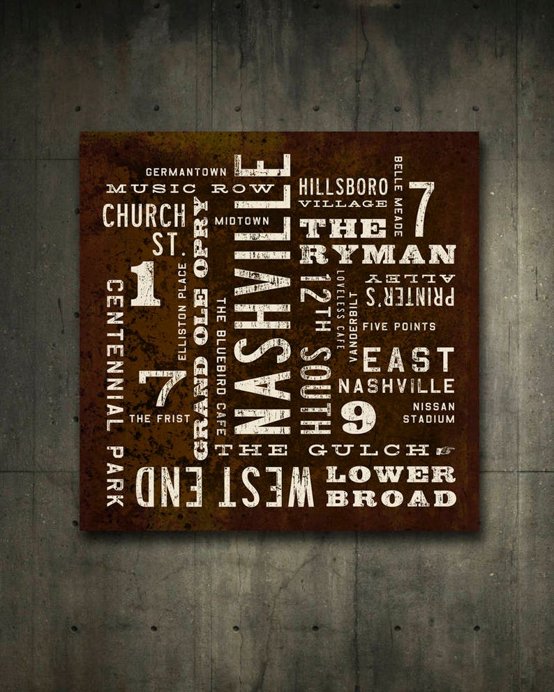 A brown and white typography poster by Transit Design with the word 'Nashville' in large white letters. The poster also includes other words related to Nashville, such as 'Music Row', 'The Ryman', '12th South', 'The Gulch', and 'West End'. The poster has a distressed, vintage look.