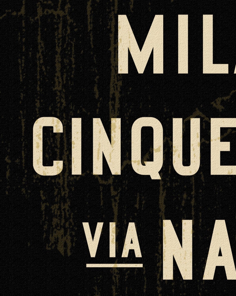 Pu&ograve; includere: Un cartello rettangolare nero con superficie testurizzata che presenta grandi lettere maiuscole sans-serif color bianco sporco. Il testo riporta MIL, CINQUE e VIA NA, con la parola VIA sottolineata. Il design ha un aspetto usurato.