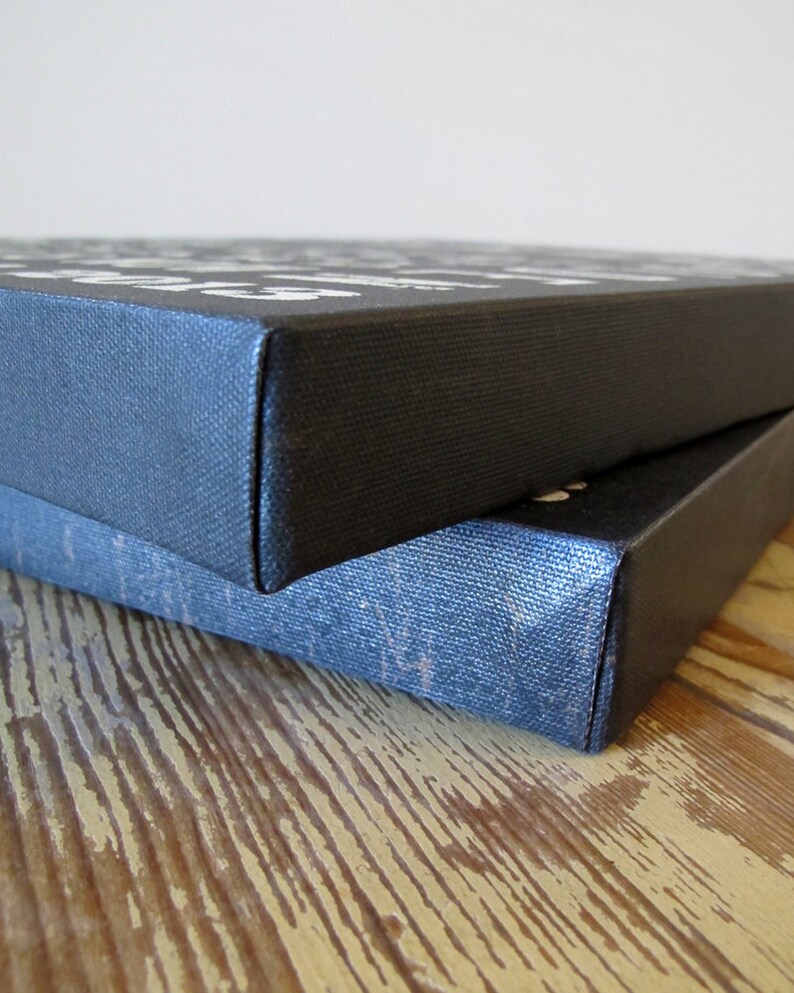 May include: Two black canvas prints stacked on top of each other. The top print has white text on it. The bottom print is slightly visible underneath the top print.