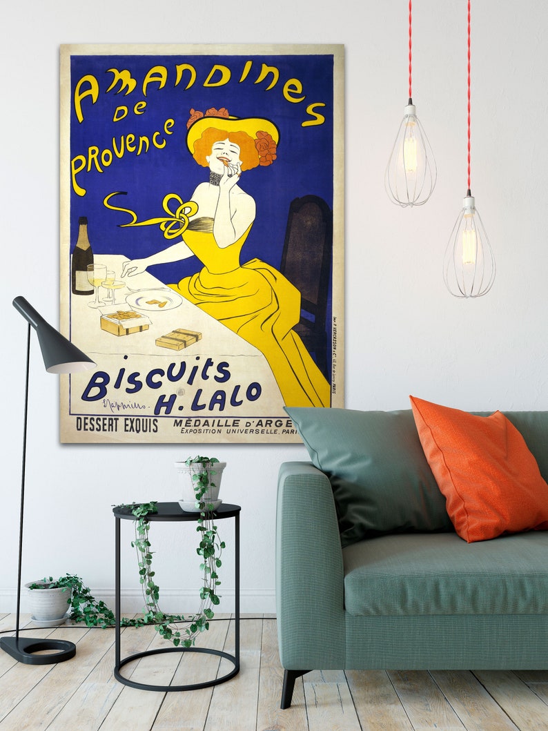 A vintage poster advertising 'Amandines de Provence' biscuits by H. Lalo. The poster features a woman in a yellow dress and a yellow hat, sitting at a table with a glass of wine and a box of biscuits. The text on the poster reads 'Amandines de Provence' 'Biscuits H. Lalo' 'Dessert Exquis' 'Médaille d'Argent Exposition Universelle, Paris'.