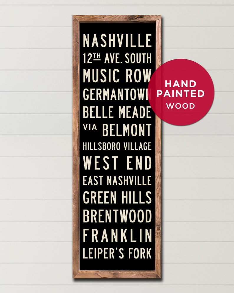 May include: Black wooden sign with white text listing various neighborhoods in Nashville, Tennessee. The sign reads "Nashville", "12th Ave. South", "Music Row", "Germantown", "Belle Meade", "Via Belmont", "Hillsboro Village", "West End", "East Nashville", "Green Hills", "Brentwood", "Franklin", and "Leiper's Fork". A red circle with white text reads "Hand Painted Wood".