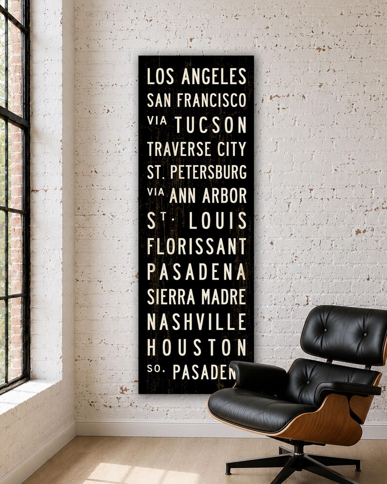 May include: A tall, rectangular black wall sign featuring white, sans-serif text listing the cities: Los Angeles, San Francisco, via Tucson, Traverse City, St. Petersburg, via Ann Arbor, St. Louis, Florissant, Pasadena, Sierra Madre, Nashville, Houston, So. Pasadena.
