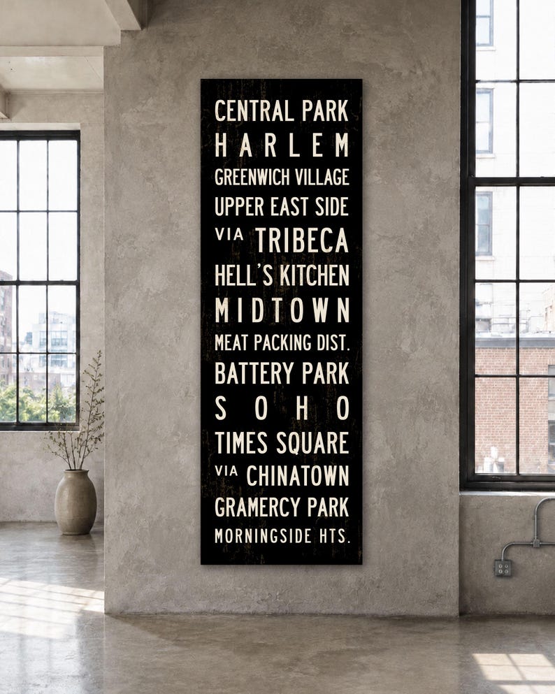 May include: A tall, rectangular black wall sign featuring white, sans-serif text listing New York City neighborhoods including Central Park, Harlem, Greenwich Village, Upper East Side, Tribeca, Hell's Kitchen, Midtown, Meat Packing Dist., Battery Park, Soho, Times Square, Chinatown, Gramercy Park, and Morningside Hts.